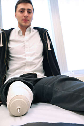 Boy sitting on examination table after limb surgery