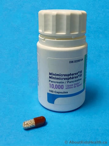 Bottle of cystic fibrosis enzymes with one capsule shown outside the bottle