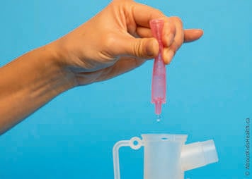 The nebule is squeezed so that medication drips into the nebulizer cup