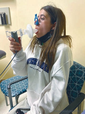 Person with nose clip blowing into a mouthpiece performing spirometry