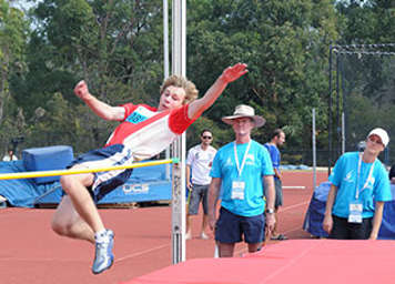 Teen boy clearing high jump bar