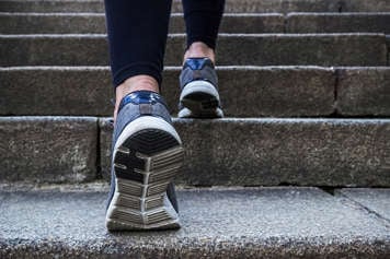 Close-up of feet walking up stairs outside